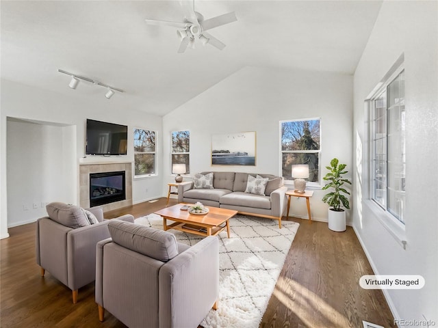 living room with hardwood / wood-style floors, vaulted ceiling, a wealth of natural light, and a tiled fireplace