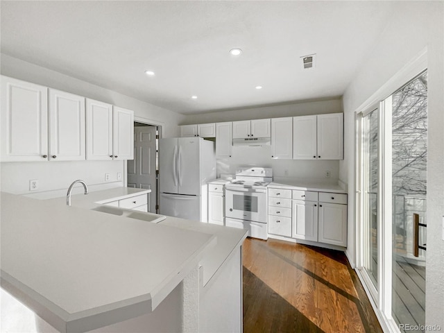 kitchen featuring kitchen peninsula, white appliances, dark wood-type flooring, sink, and white cabinetry