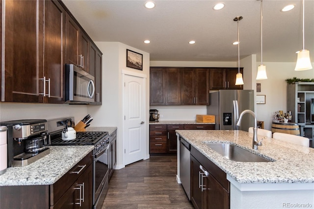 kitchen with sink, dark hardwood / wood-style flooring, stainless steel appliances, decorative light fixtures, and a center island with sink