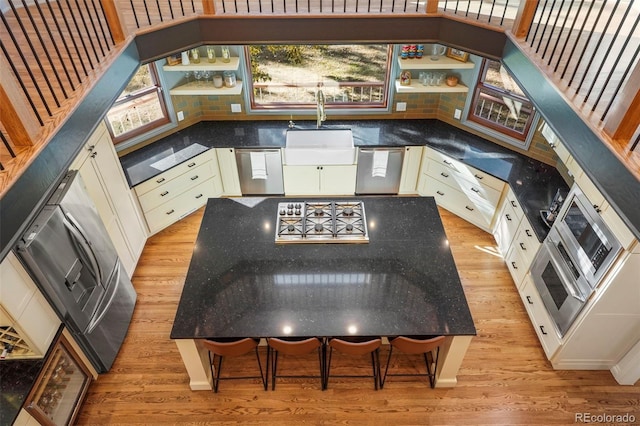 kitchen with sink, decorative backsplash, light wood-type flooring, and a healthy amount of sunlight