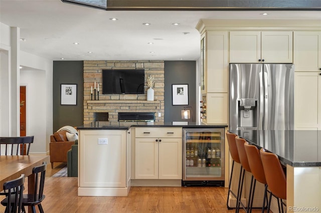 bar with wine cooler, stainless steel fridge with ice dispenser, light hardwood / wood-style flooring, and cream cabinets