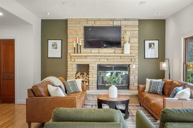 living room featuring a stone fireplace and hardwood / wood-style floors