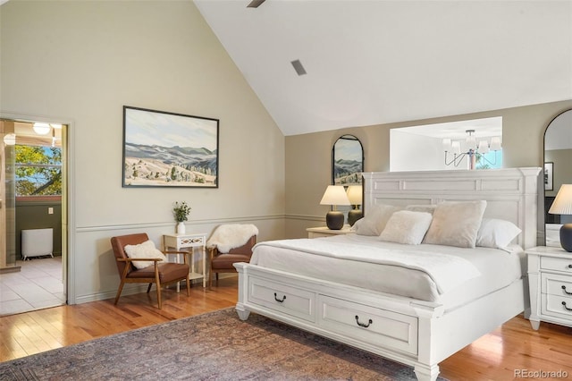 bedroom with light hardwood / wood-style floors, a chandelier, and high vaulted ceiling