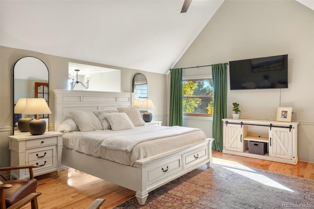 bedroom with light hardwood / wood-style flooring, high vaulted ceiling, and ceiling fan with notable chandelier