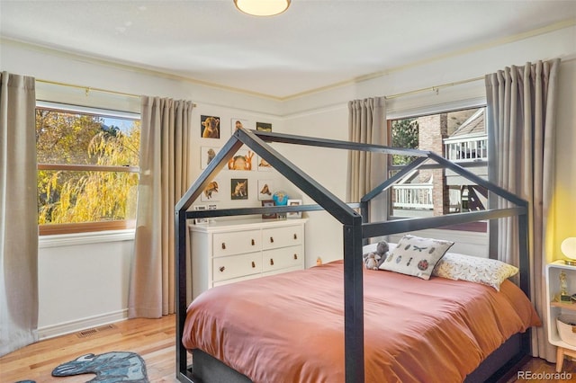 bedroom with multiple windows and light hardwood / wood-style floors