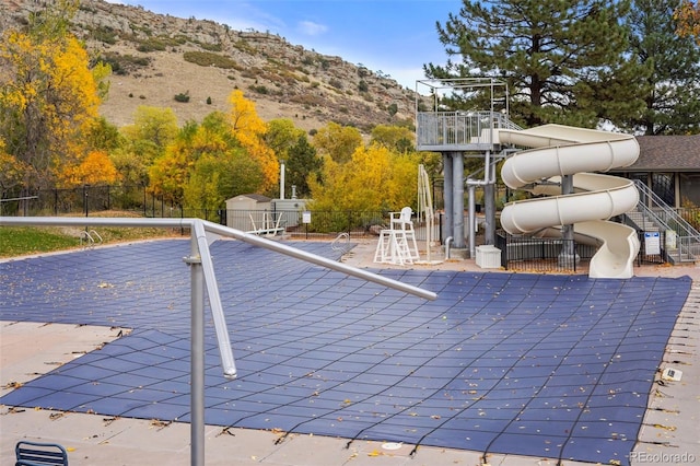 view of pool with a mountain view and a storage shed