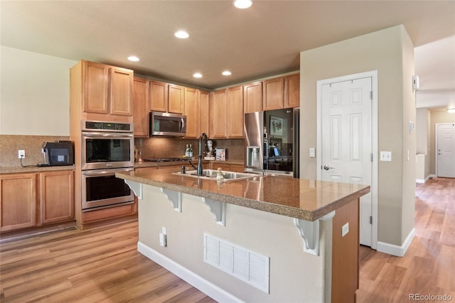 2192 Paint Pony Cir, Castle Rock, CO 80108 - kitchen featuring appliances with stainless steel finishes, a breakfast bar, tasteful backsplash, light wood finished floors, and recessed lighting