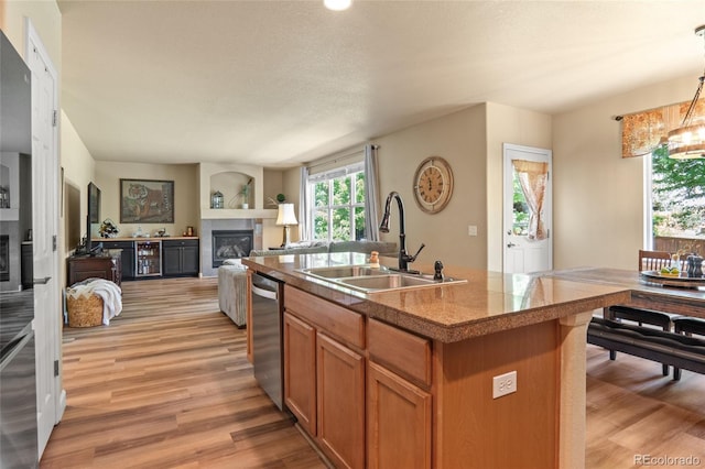 2192 Paint Pony Cir, Castle Rock, CO 80108 - kitchen featuring a glass covered fireplace, stainless steel dishwasher, light wood-style flooring, and brown cabinets