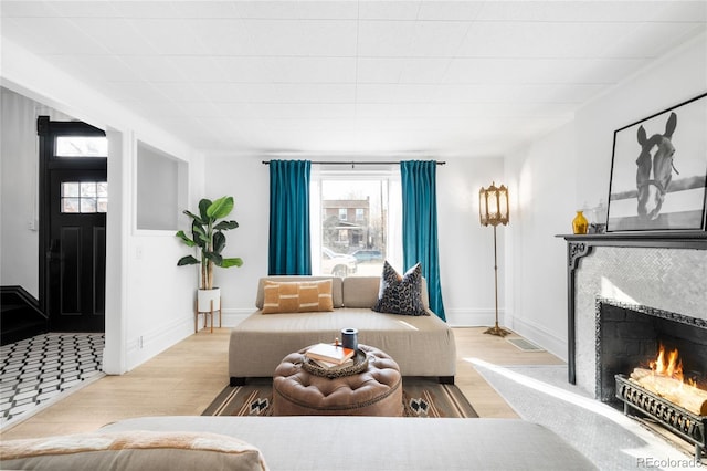 living room featuring a fireplace, baseboards, and wood finished floors