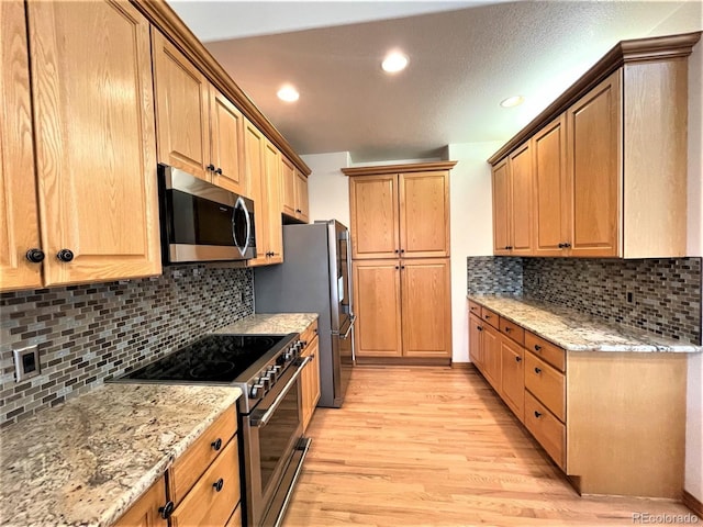 kitchen with light stone counters, stainless steel appliances, recessed lighting, tasteful backsplash, and light wood-style floors