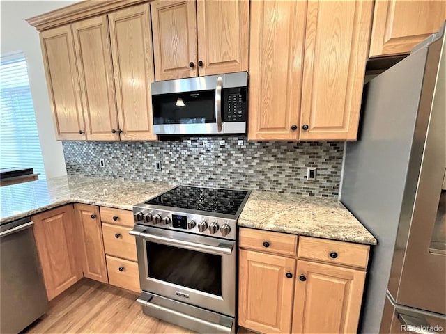 kitchen featuring light stone counters, light brown cabinets, light wood-style floors, appliances with stainless steel finishes, and backsplash