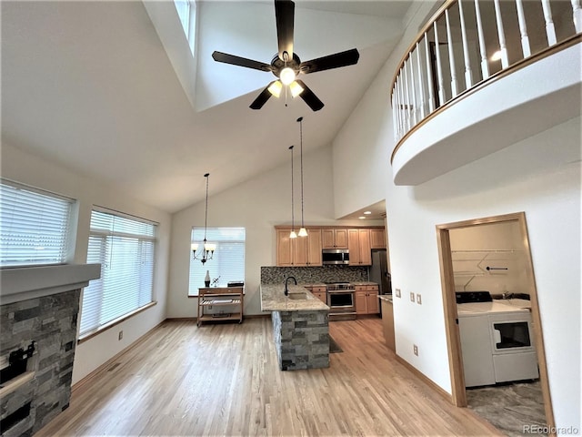 kitchen with appliances with stainless steel finishes, light brown cabinetry, light wood-style floors, washing machine and dryer, and backsplash