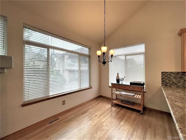 dining space with light wood finished floors, baseboards, visible vents, lofted ceiling, and an inviting chandelier