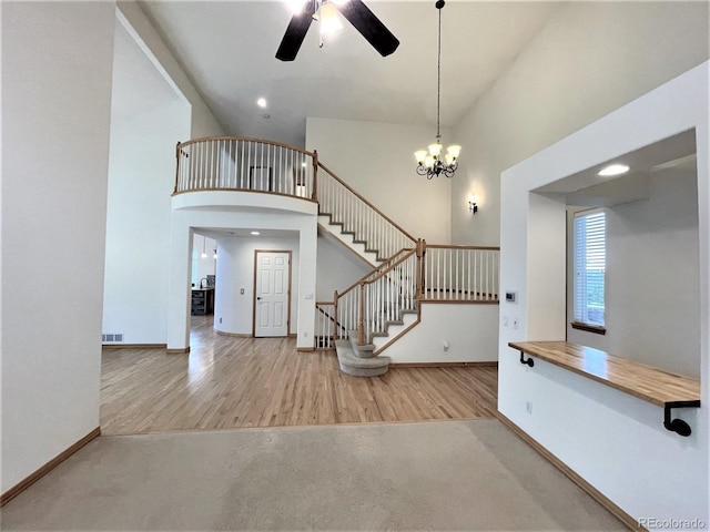 interior space with a high ceiling, wood finished floors, baseboards, stairs, and carpet