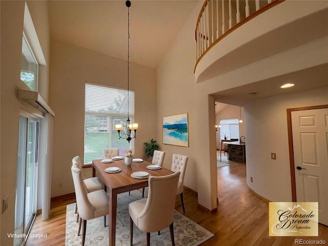 dining room featuring an inviting chandelier, light wood-style flooring, and a high ceiling