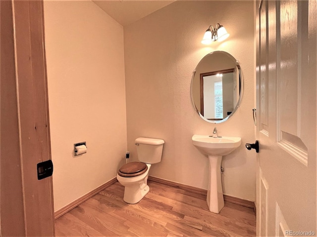 bathroom featuring a sink, wood finished floors, toilet, and baseboards