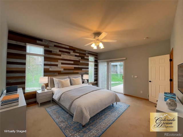 bedroom featuring access to exterior, an accent wall, wood walls, ceiling fan, and baseboards