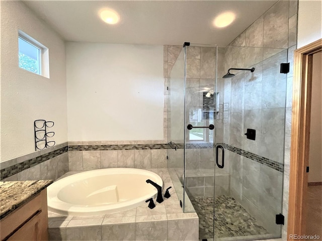 bathroom with a stall shower, vanity, and a bath