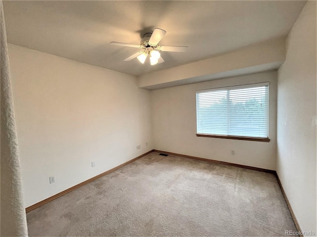 empty room featuring light carpet, ceiling fan, visible vents, and baseboards