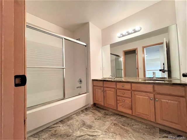 bathroom with combined bath / shower with glass door, a sink, and double vanity