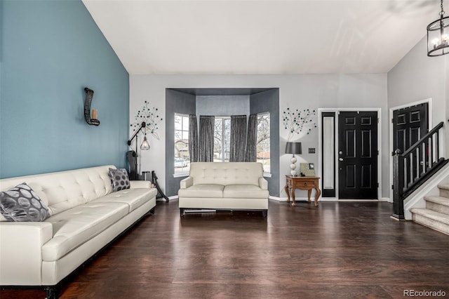 living area featuring stairway, wood finished floors, baseboards, and a notable chandelier