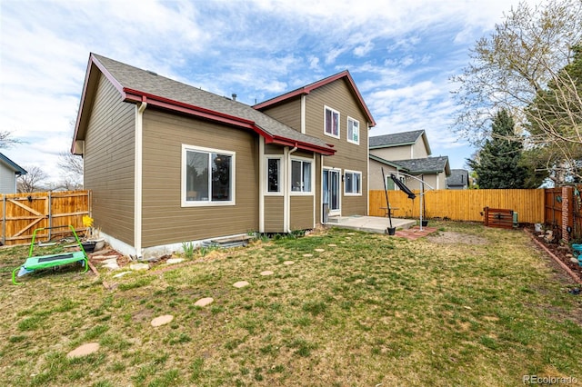rear view of property with a shingled roof, a patio area, a lawn, and a fenced backyard