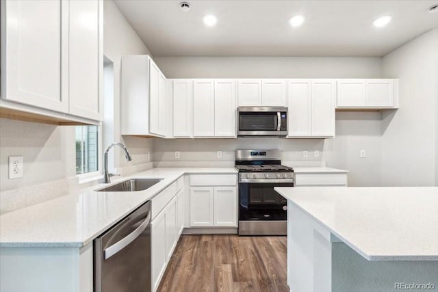 19018 E 94th Pl, Commerce City, CO 80022 - kitchen featuring appliances with stainless steel finishes, a sink, wood finished floors, white cabinetry, and recessed lighting