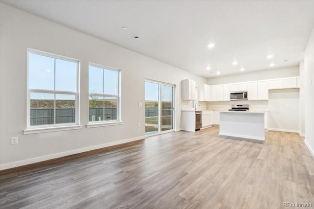 19018 E 94th Pl, Commerce City, CO 80022 - unfurnished living room with light wood-type flooring, baseboards, and recessed lighting