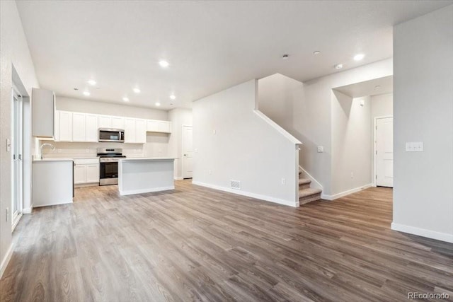 19018 E 94th Pl, Commerce City, CO 80022 - kitchen featuring appliances with stainless steel finishes, open floor plan, wood finished floors, baseboards, and light countertops