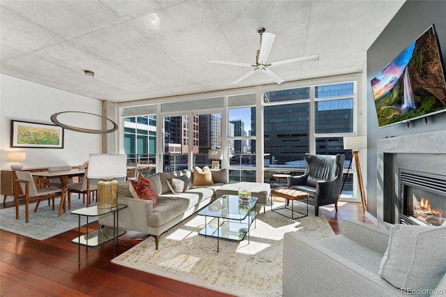 interior space with expansive windows, a ceiling fan, a fireplace, and wood finished floors