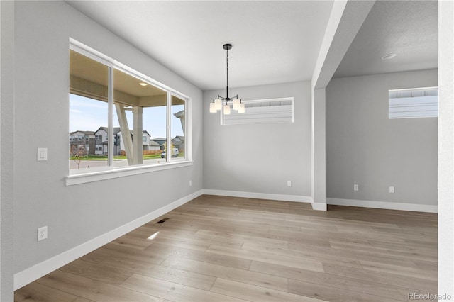 unfurnished dining area featuring light hardwood / wood-style flooring and an inviting chandelier