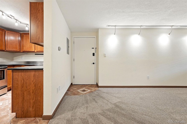 1045 N Clarkson St Unit 102, Denver, CO 80218 - kitchen with a textured ceiling, brown cabinetry, light colored carpet, electric panel, and stainless steel electric range oven