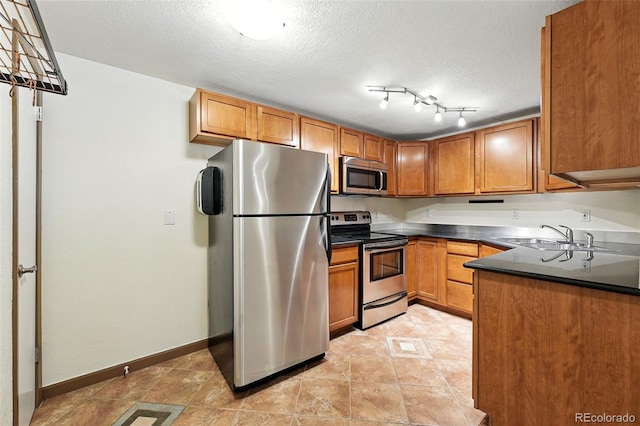 1045 N Clarkson St Unit 102, Denver, CO 80218 - kitchen featuring stainless steel appliances, brown cabinetry, dark countertops, and a textured ceiling