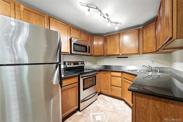 1045 N Clarkson St Unit 102, Denver, CO 80218 - kitchen featuring stainless steel appliances, a textured ceiling, brown cabinetry, dark countertops, and light tile patterned flooring