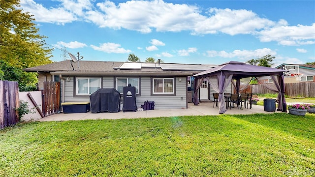 41 S Fenton St, Lakewood, CO 80226 - back of property with roof mounted solar panels, a patio, a fenced backyard, a gazebo, and a shingled roof