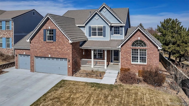 traditional-style house featuring a porch, an attached garage, concrete driveway, a tiled roof, and brick siding