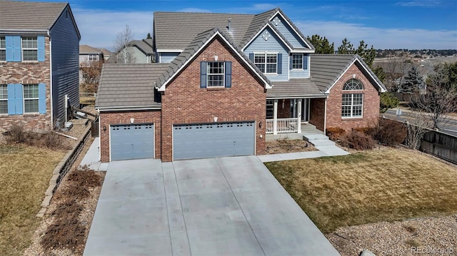 traditional-style home featuring a tile roof, concrete driveway, a front yard, an attached garage, and brick siding