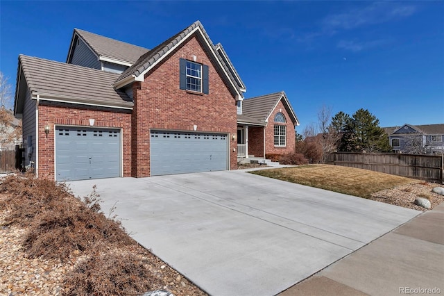 traditional-style home with brick siding, fence, a tiled roof, concrete driveway, and an attached garage