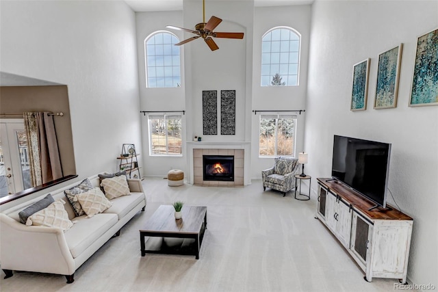 living area with a ceiling fan, a high ceiling, a fireplace, and carpet flooring