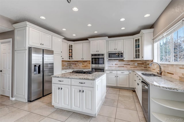 kitchen with white cabinets, appliances with stainless steel finishes, a kitchen island, and a sink