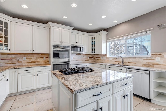 kitchen with light tile patterned floors, a sink, decorative backsplash, white cabinets, and appliances with stainless steel finishes