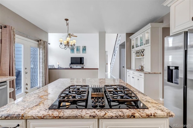 kitchen featuring stainless steel fridge, white cabinetry, and black gas stovetop