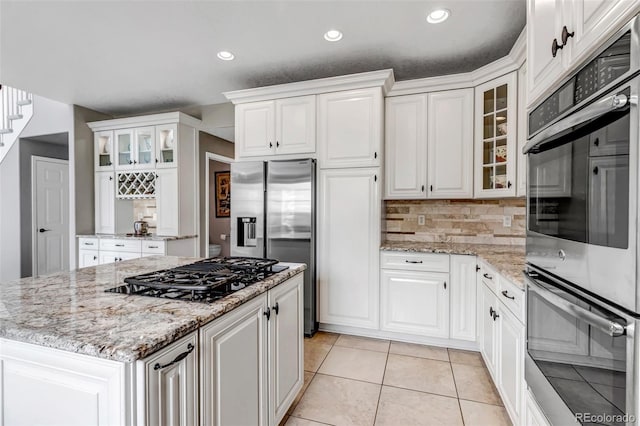 kitchen with white cabinetry, light tile patterned floors, a kitchen island, and stainless steel appliances