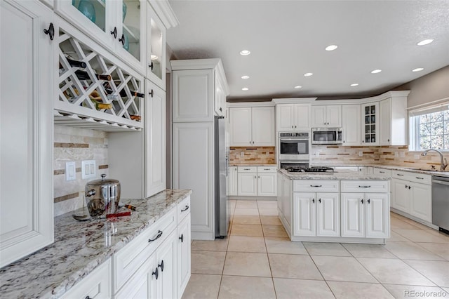 kitchen with light tile patterned floors, white cabinets, appliances with stainless steel finishes, and a sink