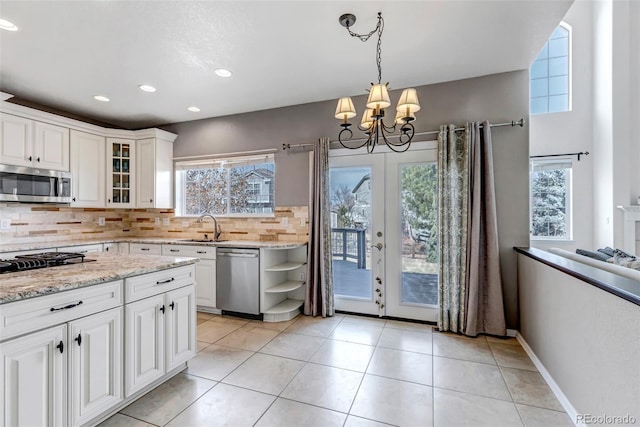 kitchen featuring glass insert cabinets, backsplash, appliances with stainless steel finishes, and a healthy amount of sunlight