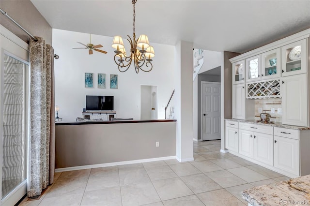 kitchen with hanging light fixtures, light tile patterned floors, white cabinets, and glass insert cabinets