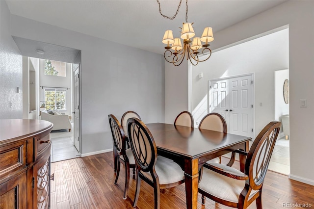 dining area featuring an inviting chandelier, wood finished floors, and baseboards