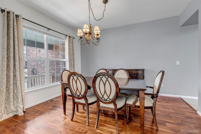 dining area featuring visible vents, baseboards, an inviting chandelier, and wood finished floors