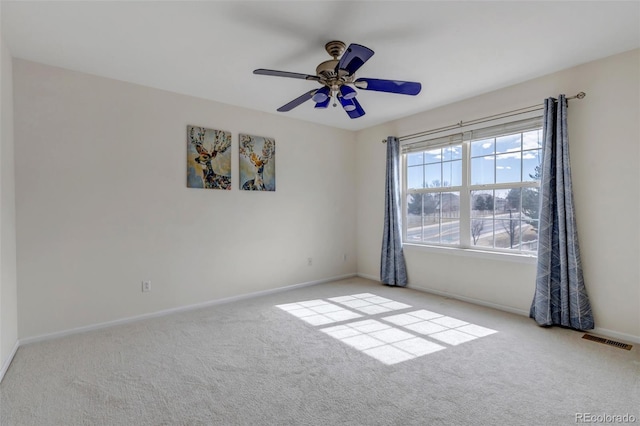 carpeted spare room featuring visible vents, baseboards, and ceiling fan