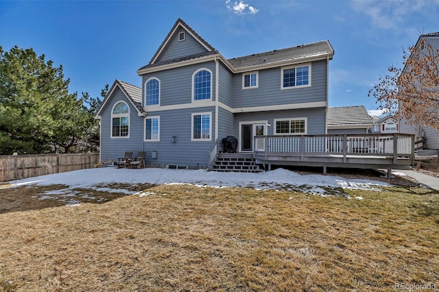 snow covered house featuring a wooden deck and fence